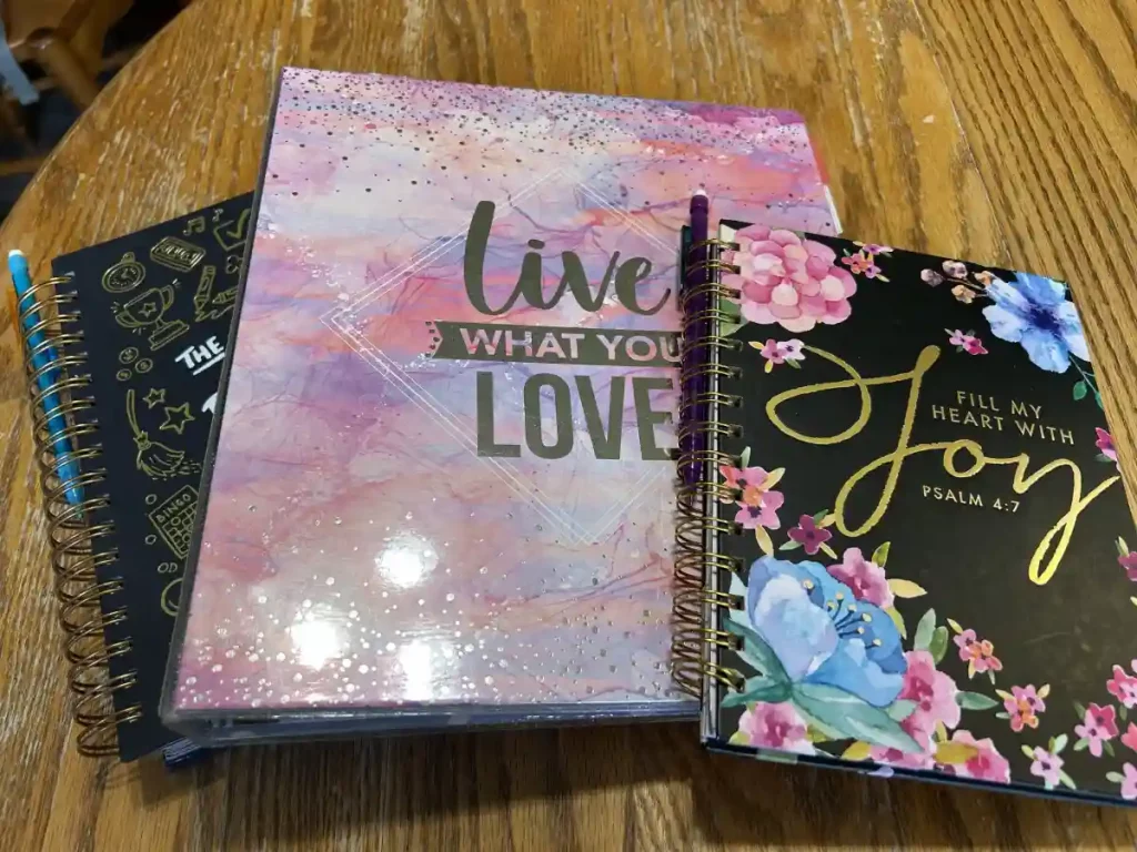 Two colorful notebooks and a binder fanned out on a wooden surface.